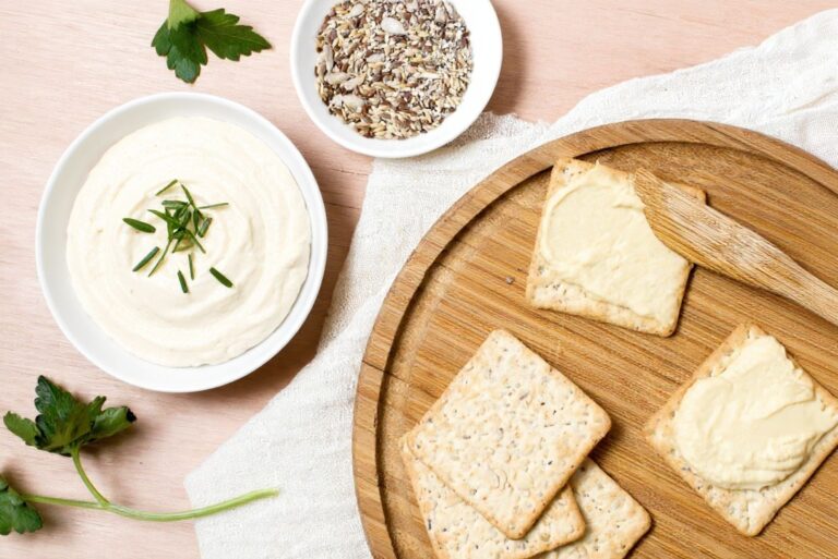 Una ciotola di crema di tofu con un piatto di crackers con la crema spalmata sopra