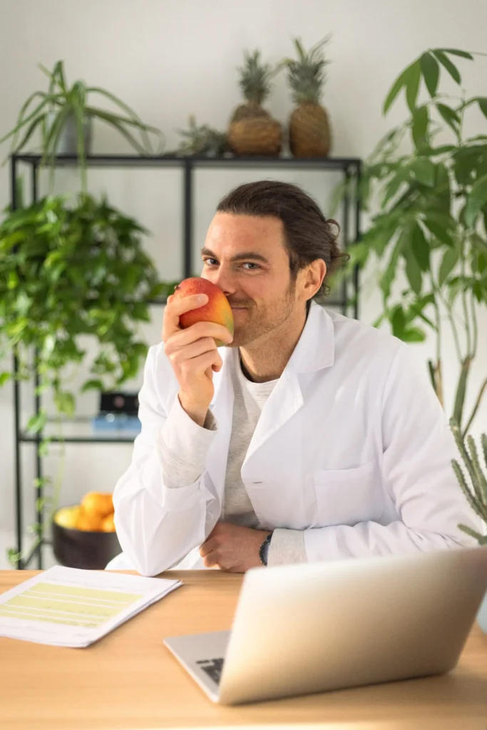 Il nutrizionista Giovanni Brugnolaro alla scrivania che annusa un mango