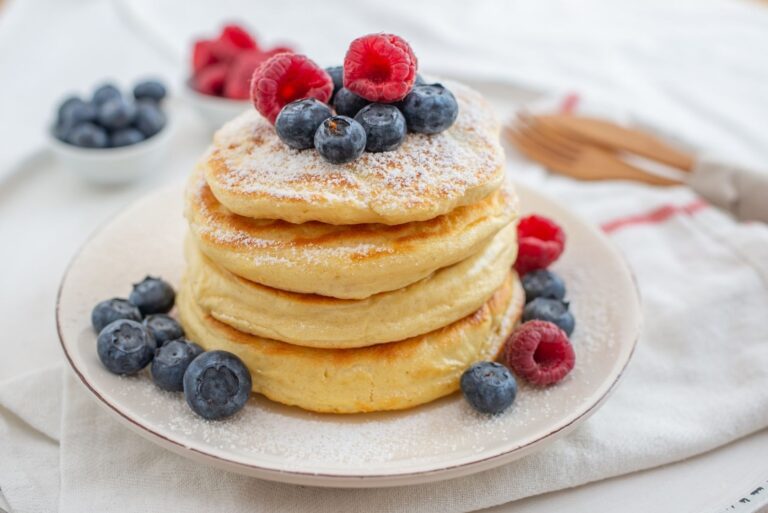 Una pila di pancake all'avena su un piatto decorati con lamponi e mirtilli