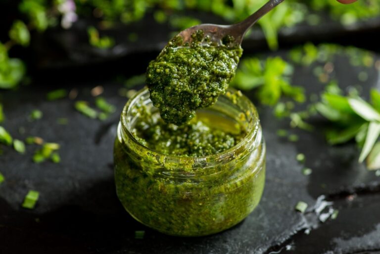 Un vasetto di pesto vegano in primo piano su sfondo nero